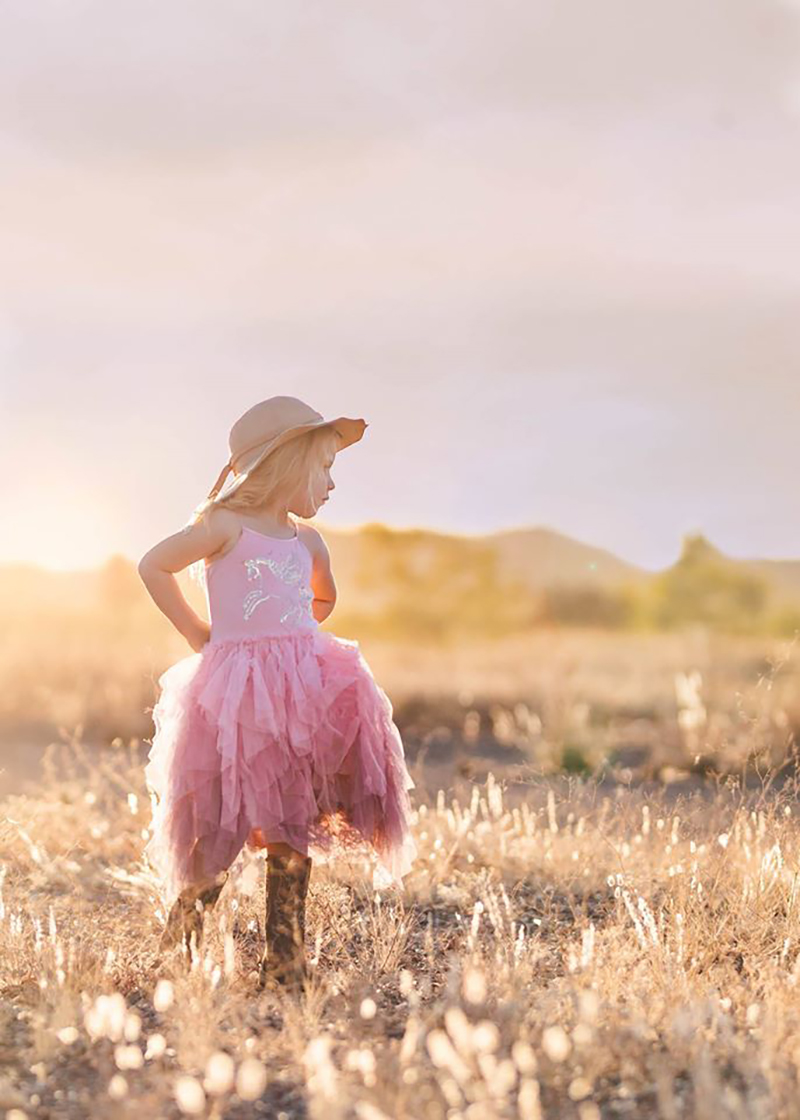 little girl wearing a pink dress outdoors during golden hour