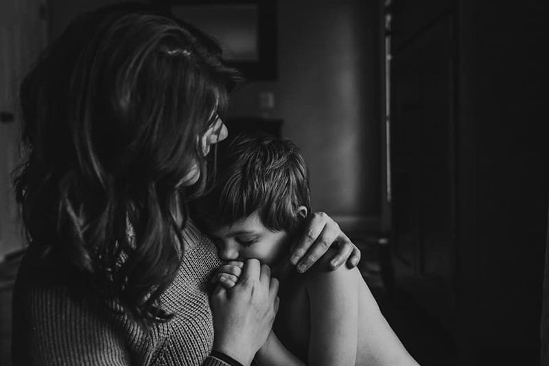 dramatic dark and moody photography of mother and son holding hands