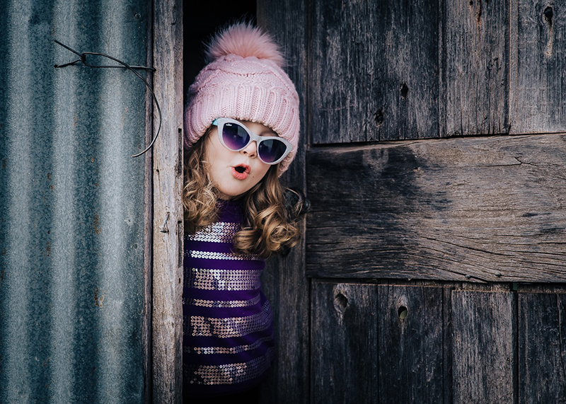 pink photo of girl opening door wearing a pink beanie 