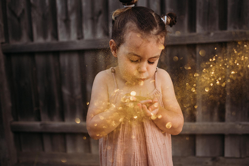 image of little girl blowing glitter 