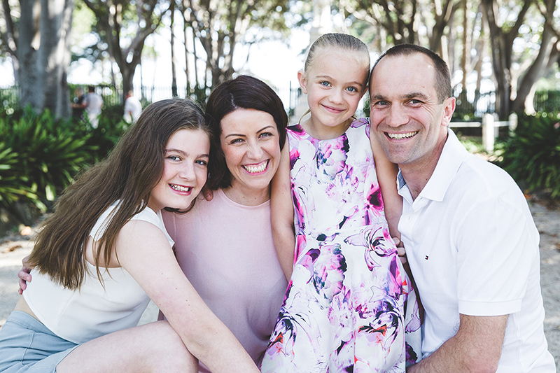 smiling family photo of couple with two daughters