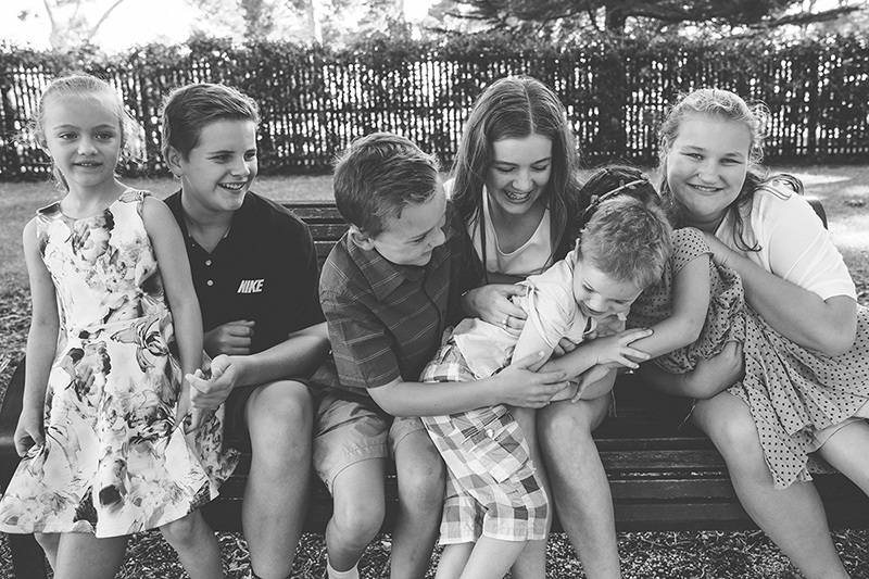 family photo of children sitting on bench and laughing