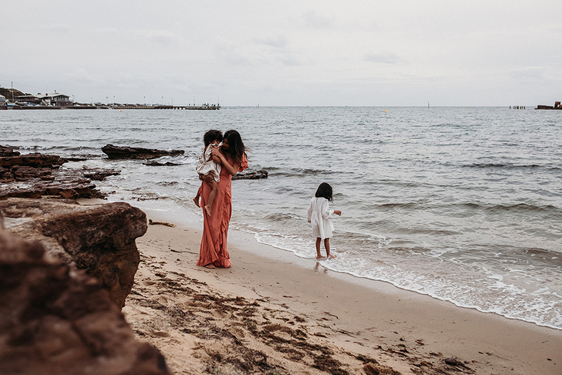 mother walking on the beach with two daughters
