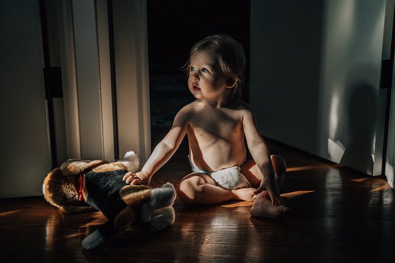 low light portrait of toddler playing with fluffy toy