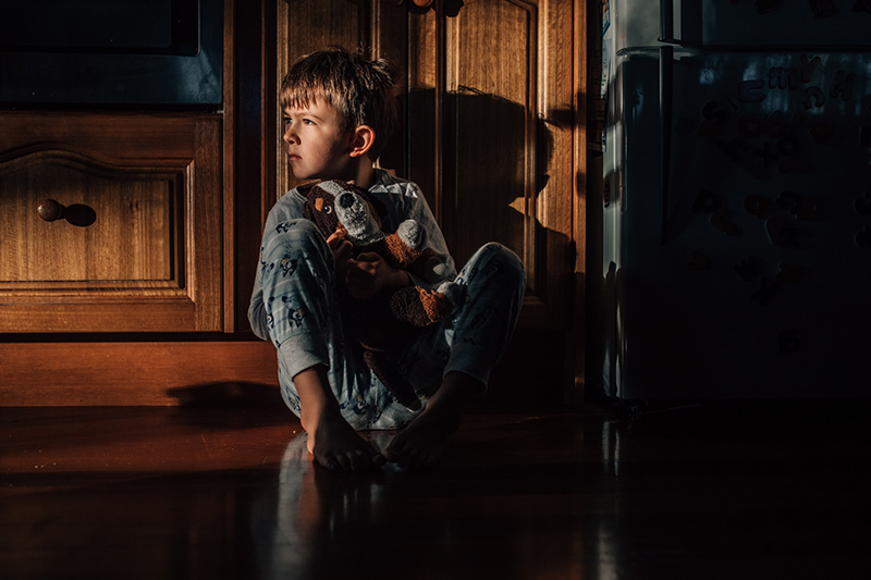 little boy in pocket of natural light holding a toy