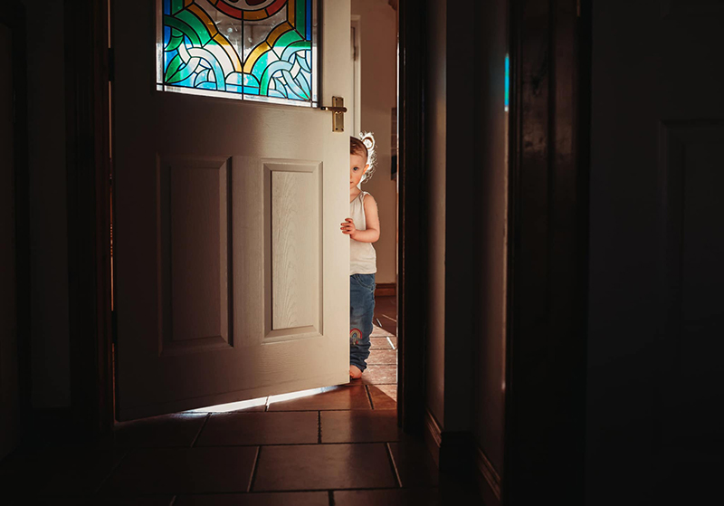 low light photo of little boy behind a door