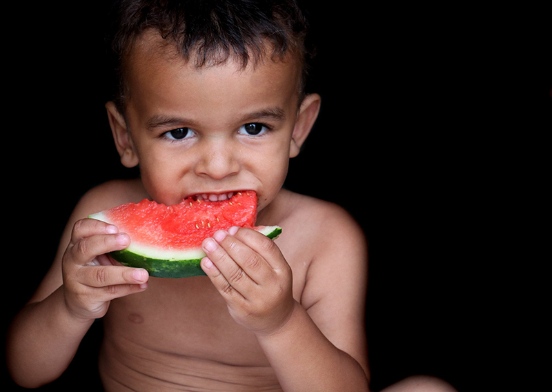  little boy eating watermelon under pocket of natural light