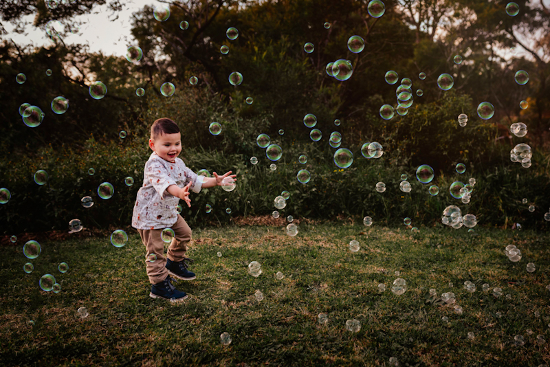 bubble pictures of toddler boy chasing bubbles in the woods