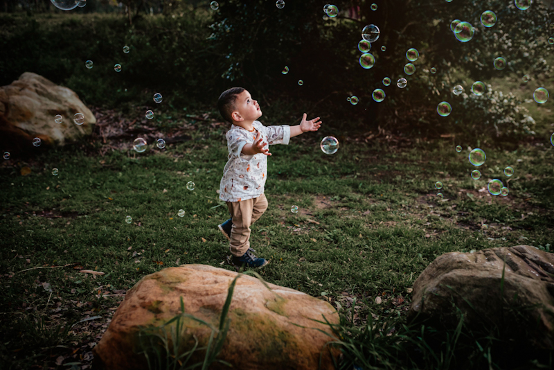 little boy trying to catch bubbles in bubble photography