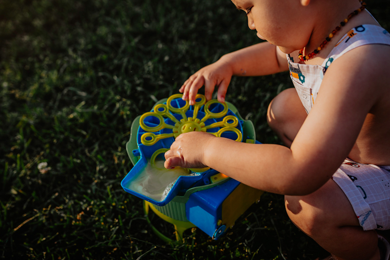 toddler playing with bubble machine