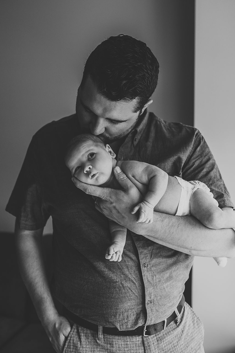 black and white newborn photography of man kissing baby