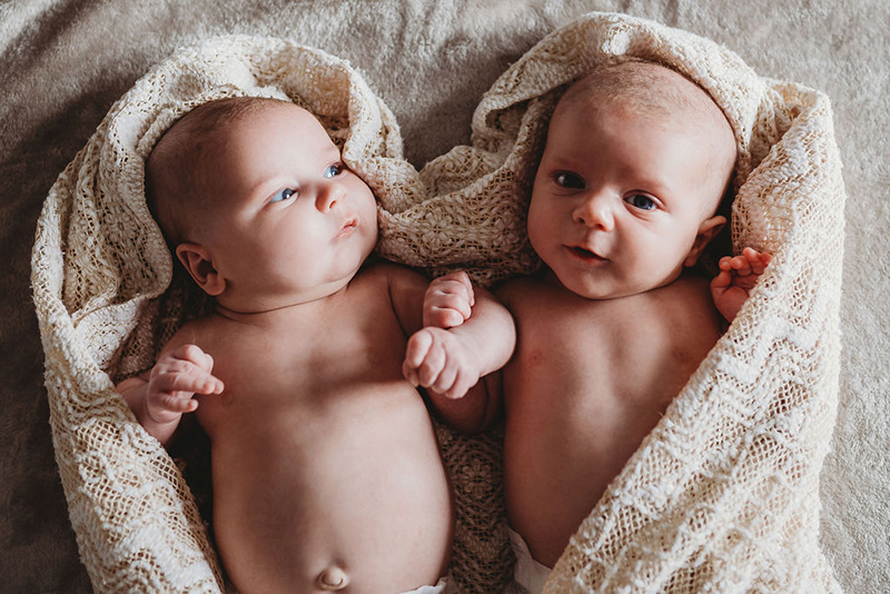 newborn twins photo wrapped in heart-shaped blanket