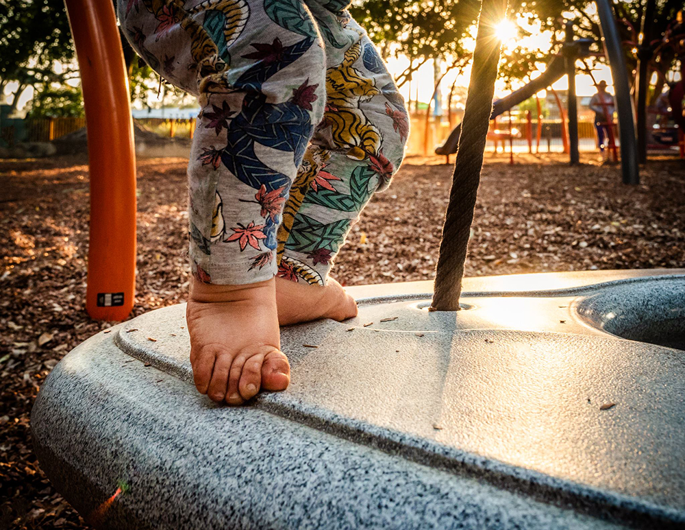 toddler on playground equipment at a park during the golden hour