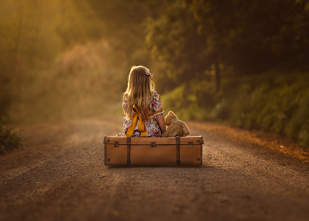 backlighting portraits girl on the road with luggage and teddy bear
