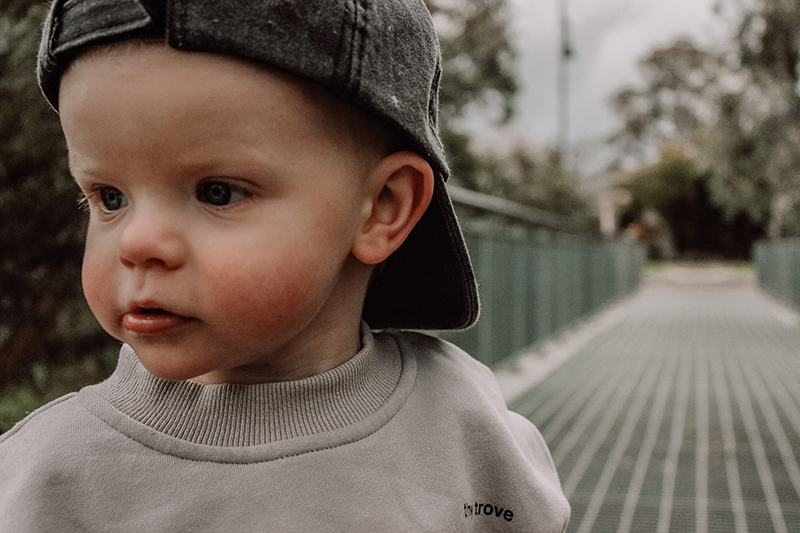 close up photo of toddler boy wearing a cap backwards