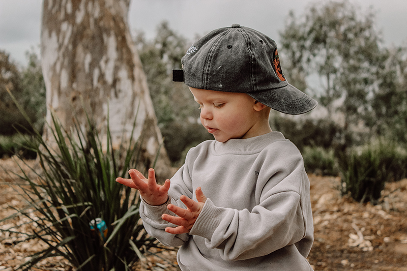 photography course toddler boy in backwards cap looking at his hands
