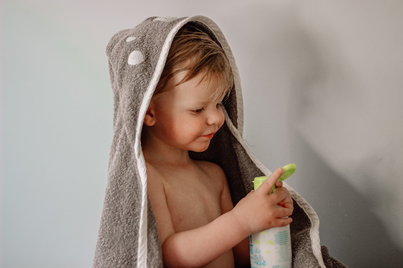 toddler boy wearing hooded towel and holding a bottle