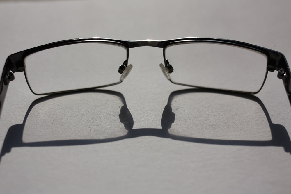 still life photo of reading glasses and a reflected shadow