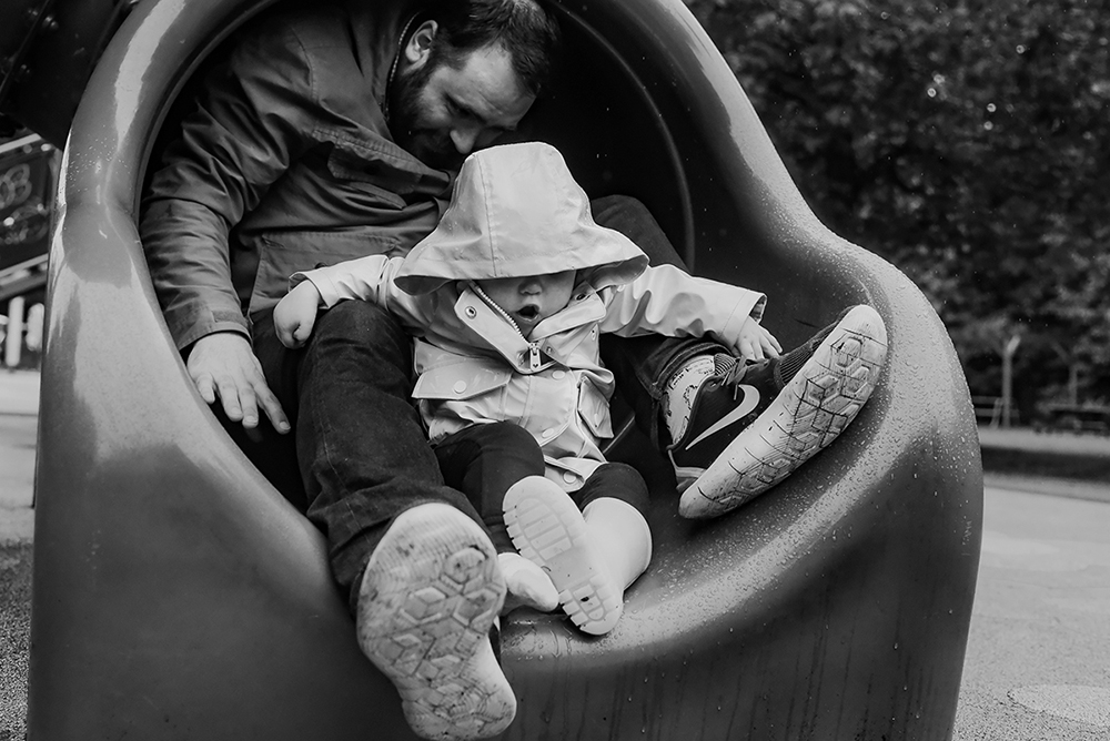 toddler girl and father on a park playground slide
