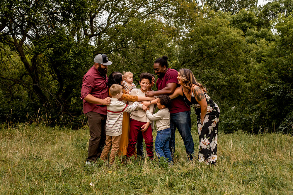 two families hugging with children in a field