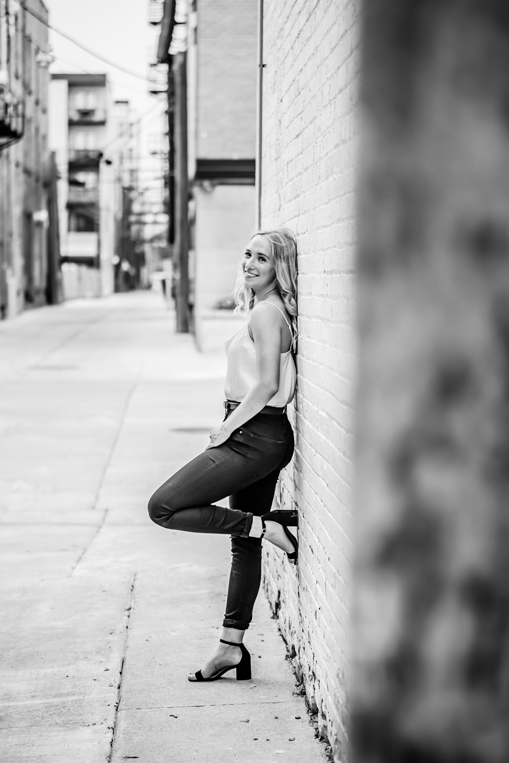 senior girl standing and leaning against an urban wall