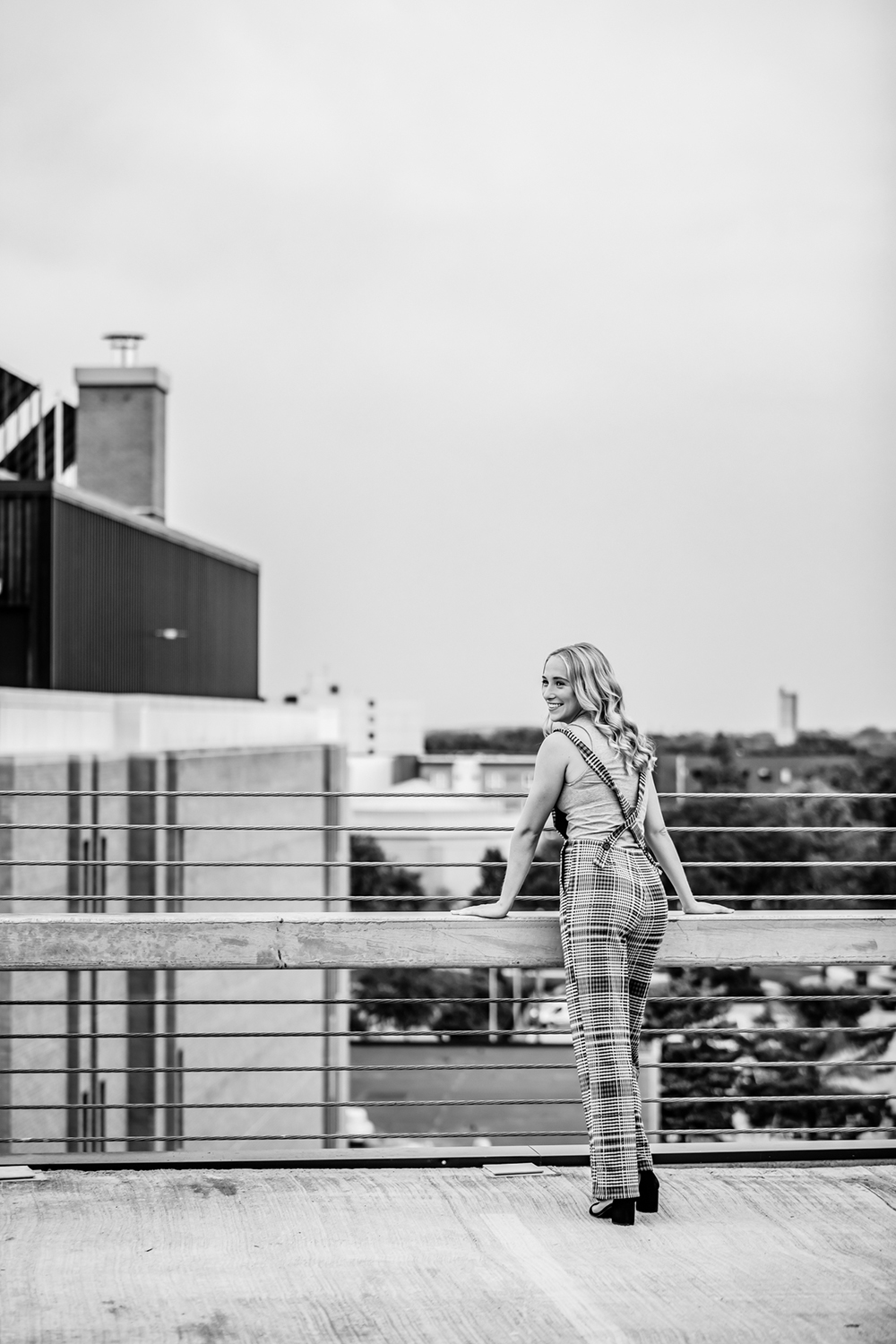 black & white photo of a girl posing with the city in the distance