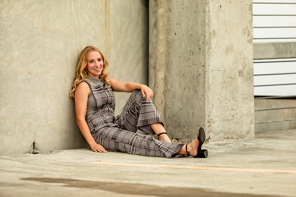 grads photography portrait of girl sitting leaning against a wall