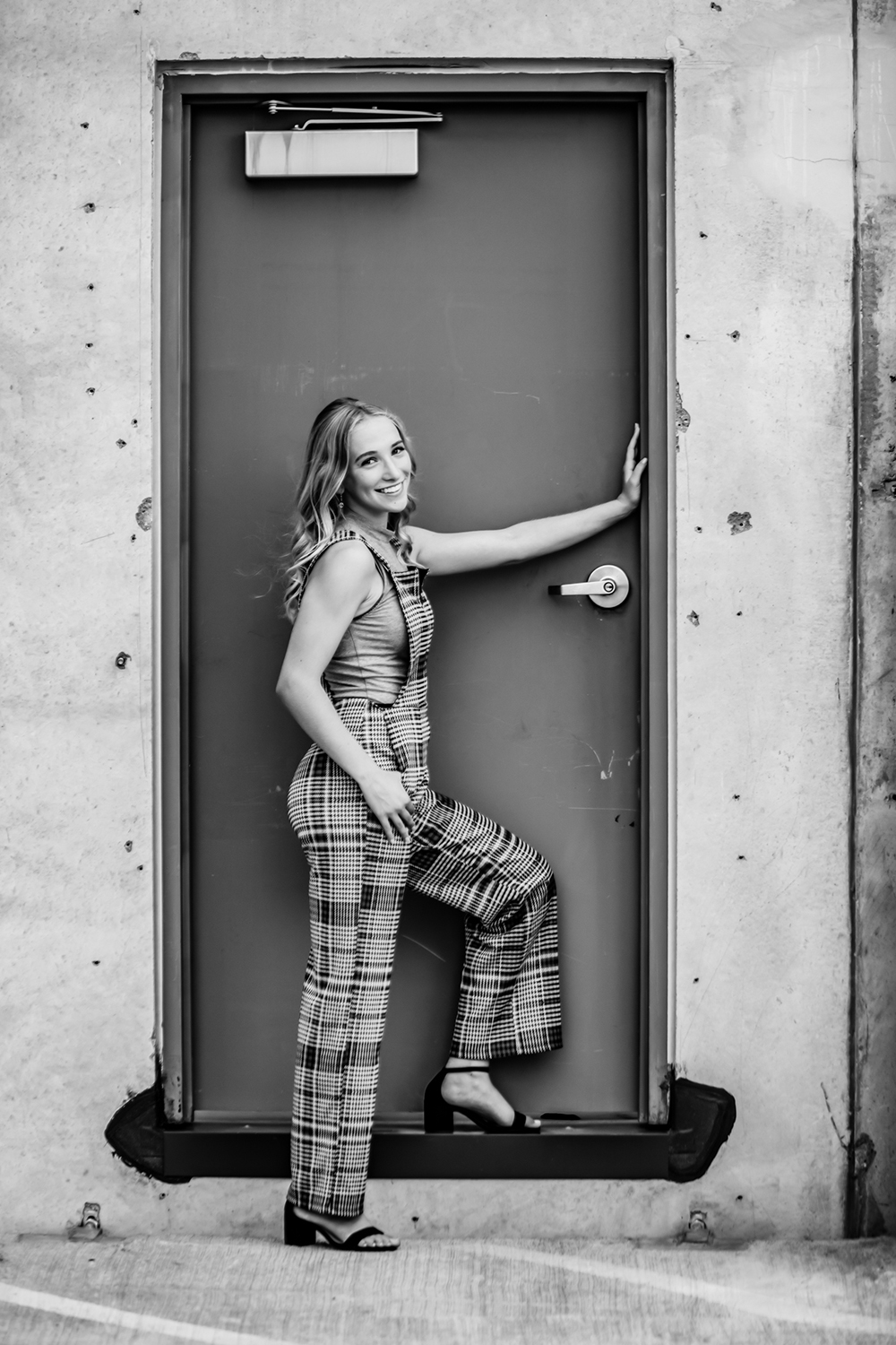 senior girl with long blonde hair standing in a doorway