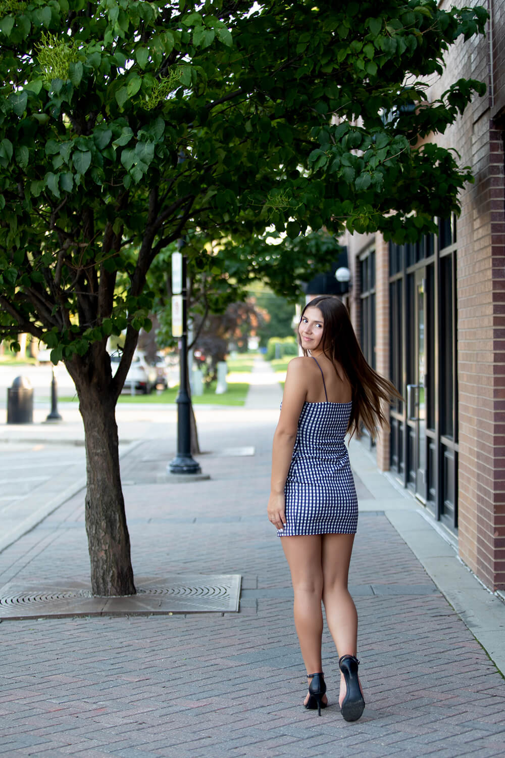grad photography session with teen girl walking down an urban street and looking back