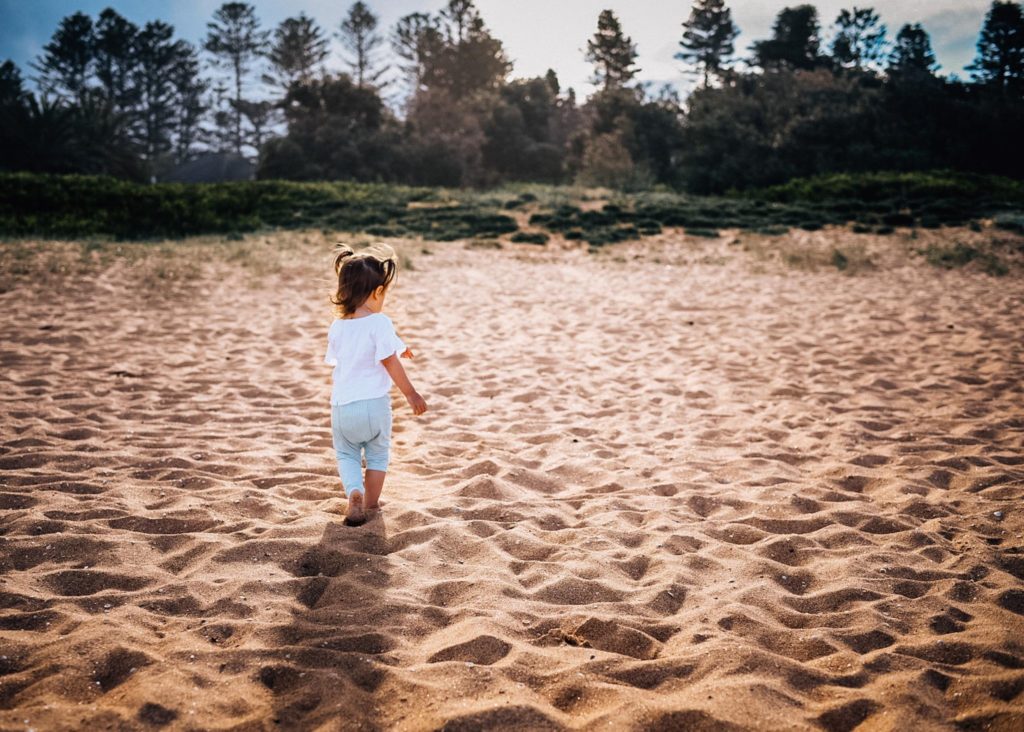 toddler girl in blue shorts walking on a beach photography lessons