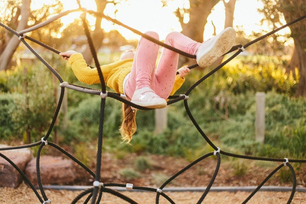 Young girl upside down on climbing frame