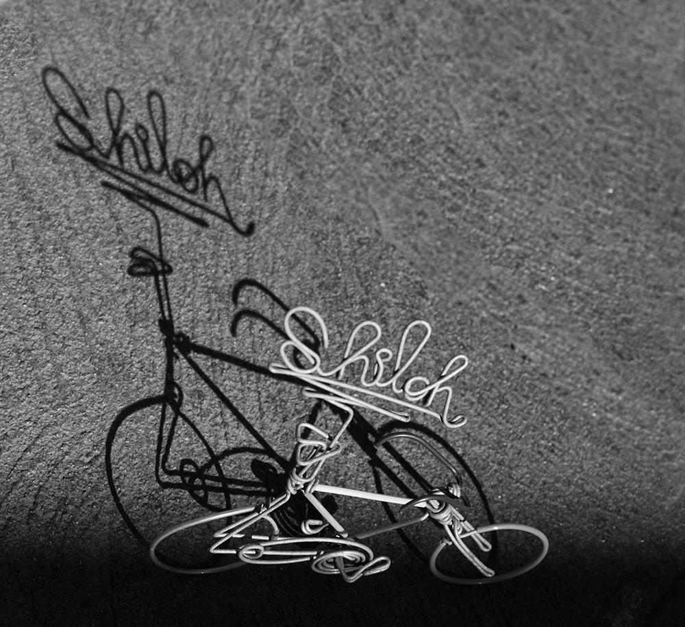 still life photo of a miniature bicycle made of wire 