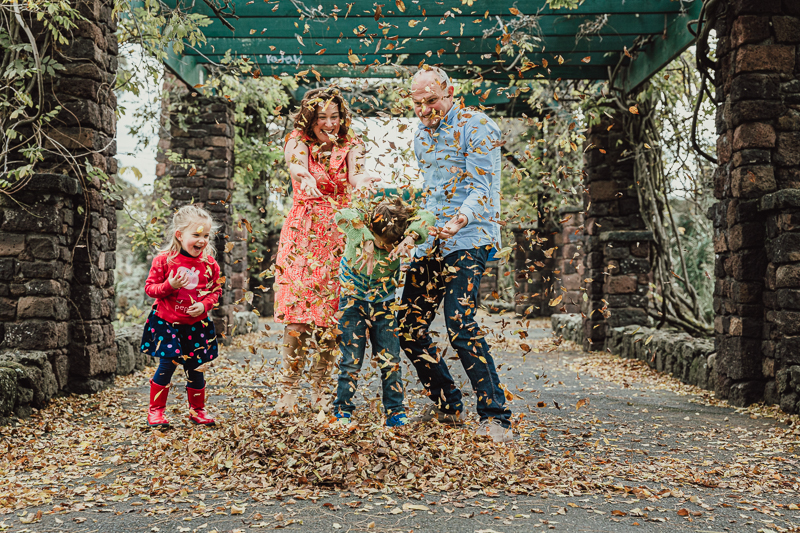 mum dad and girl and boy throwing autumn leaves
