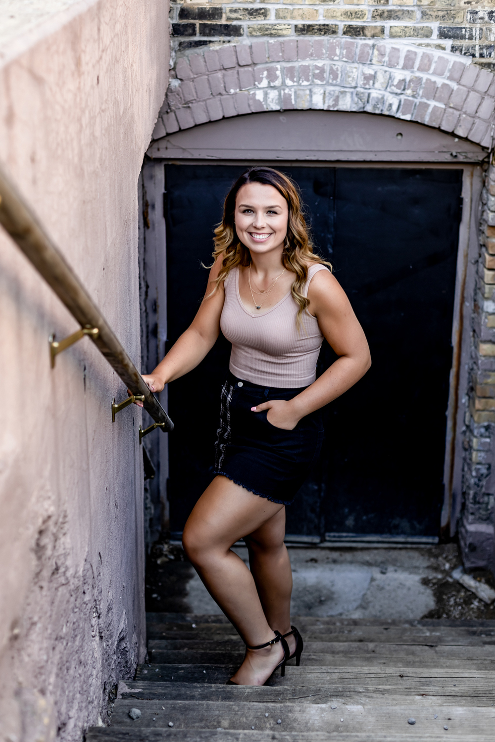 teenage girl poses in a stairwell wearing a black skirt