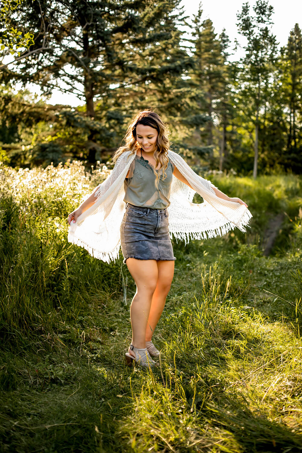 grads photography session photo of a girl twirling in a field with her arms outstretched