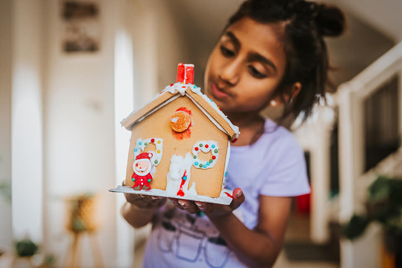 girl decorating a gingerbread house