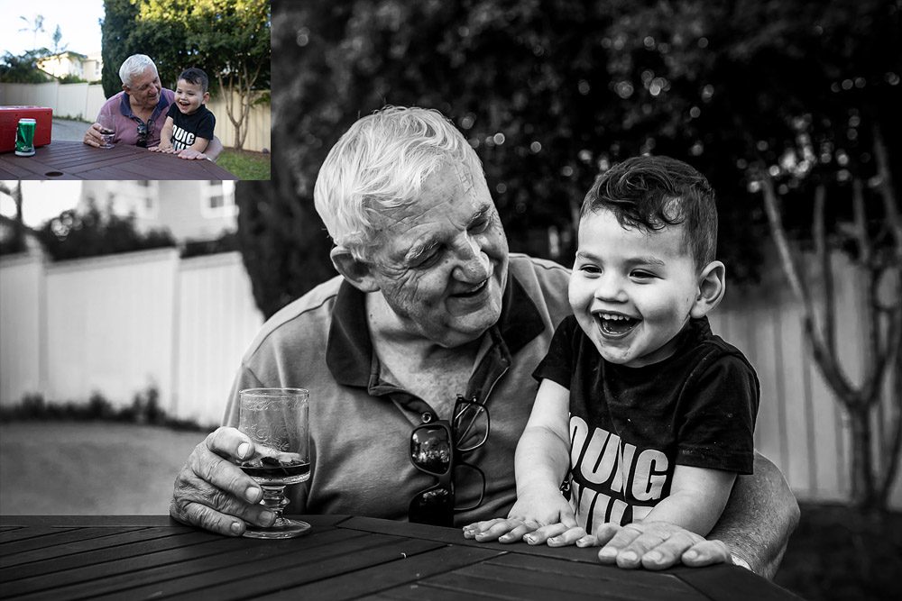 grandfather and toddler boy sitting at an outside table laughing