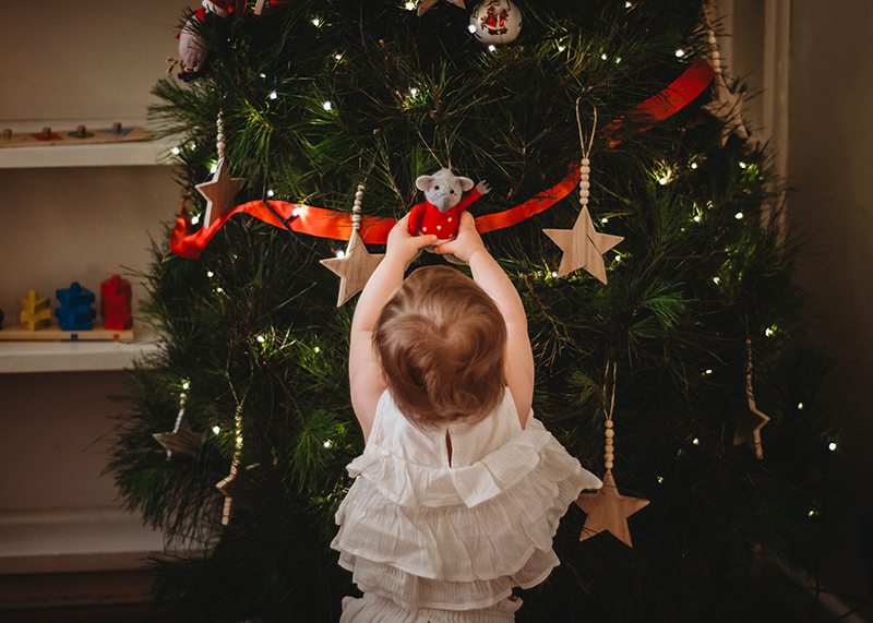 baby girl standing at a christmas tree