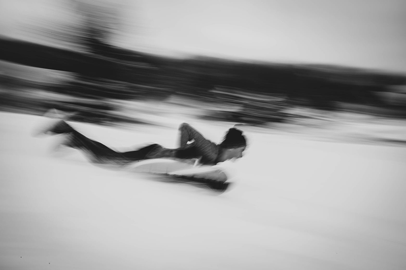 b&w photo of a man on a sled