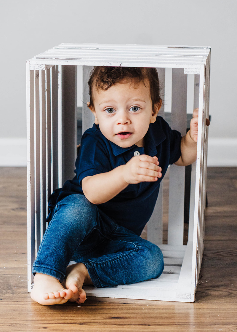 studio portraits of little boy inside white wooden crate
