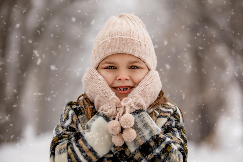 girl in pink beanie and mittens in the snow