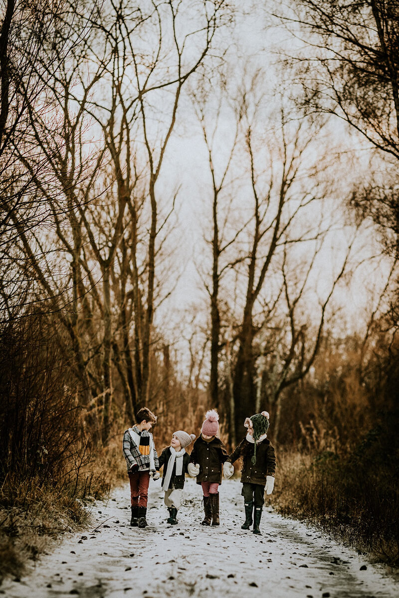 four children walking along a forest path in the snow