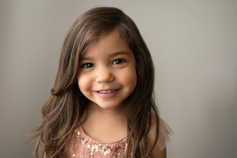 home portrait of little girl smiling wearing pink sequin dress