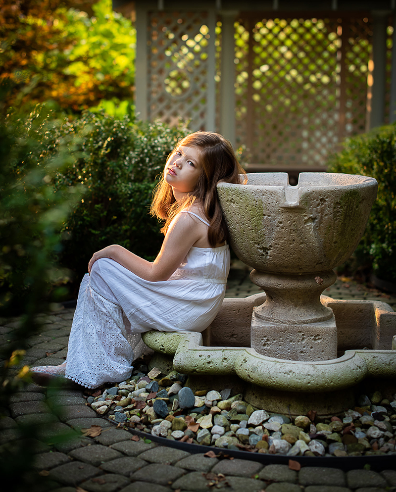 backlighting photo of young girl sitting in a garden