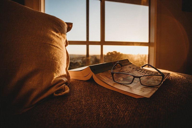 glasses and book in sunlight on a chair