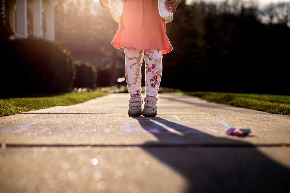 faceless portrait of toddler girl playing hopscotch
