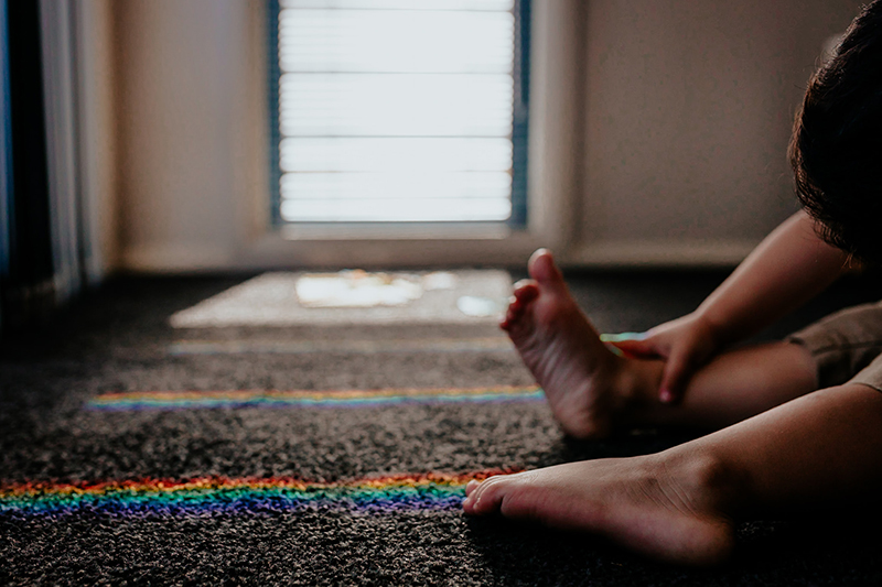 toddler feet on carpet with rainbow reflection in front of a window