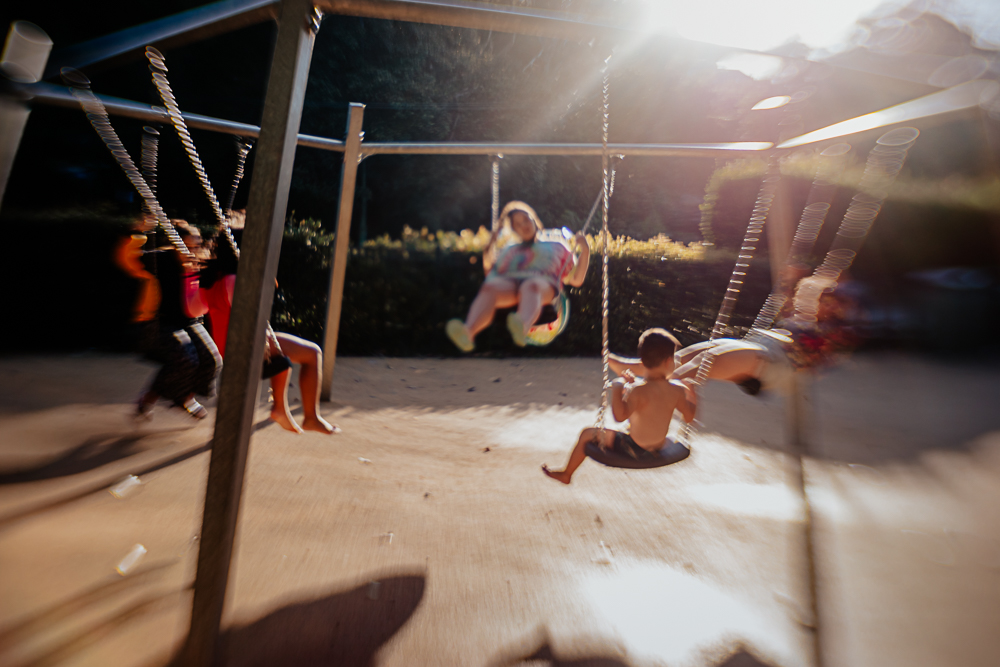 Five children on swings at the park at golden hour