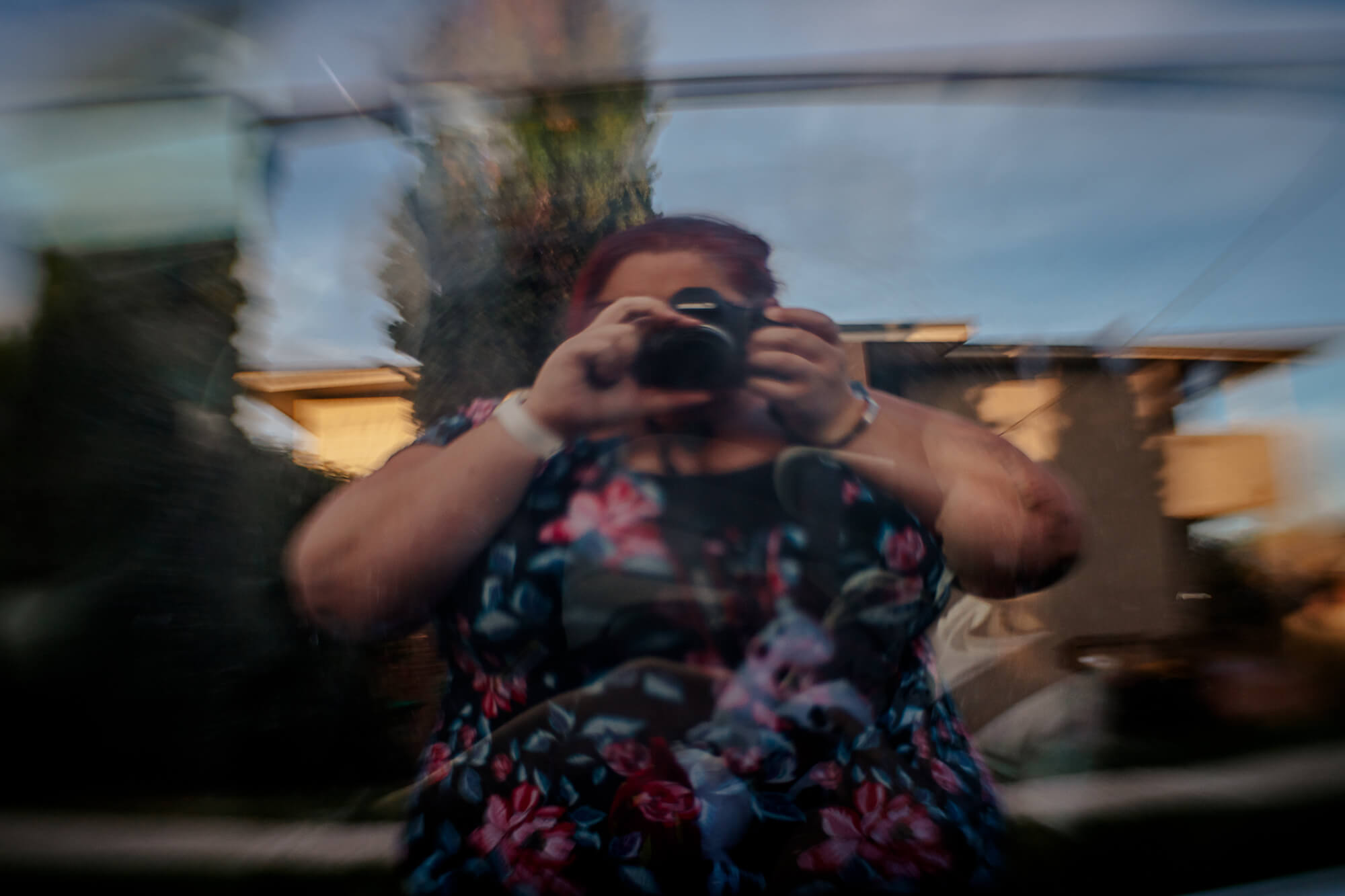 self portrait of woman in flower dress reflected in glass