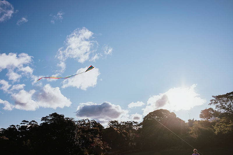 kite flying in blue sky with clouds and sun haze